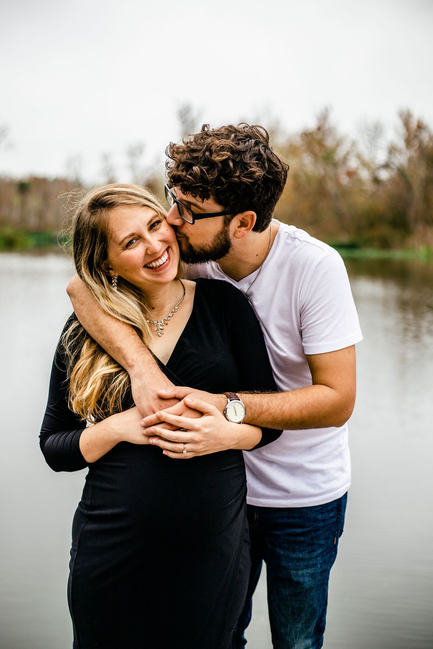 Pregnant wife smiling with her husband kissing her cheek