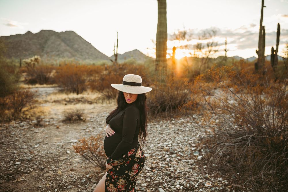 women wearing a hat looking down and holding her belly