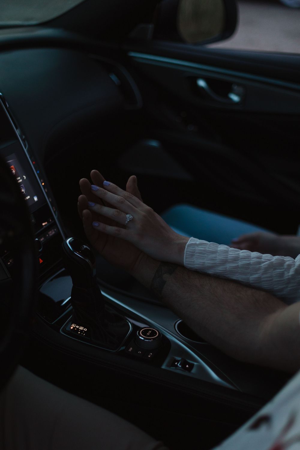 Hand resting on a car's center console showing the gear shift and interior controls.