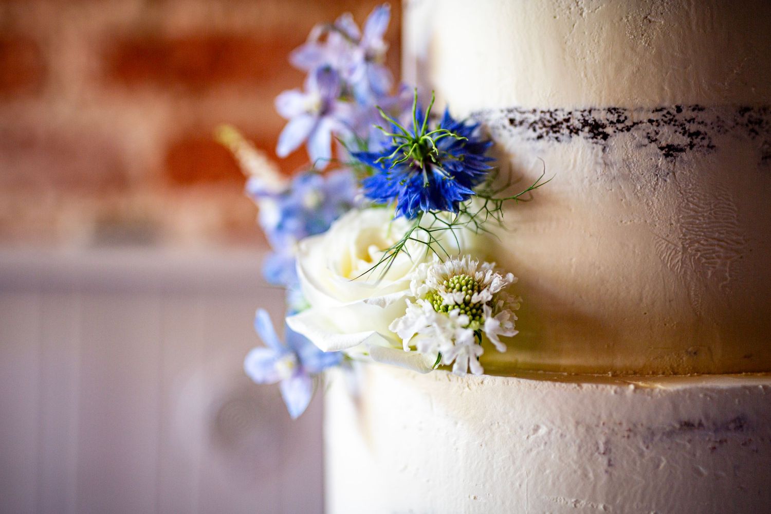 Wedding cake decorated with delicate blue and white flowers in soft focus.