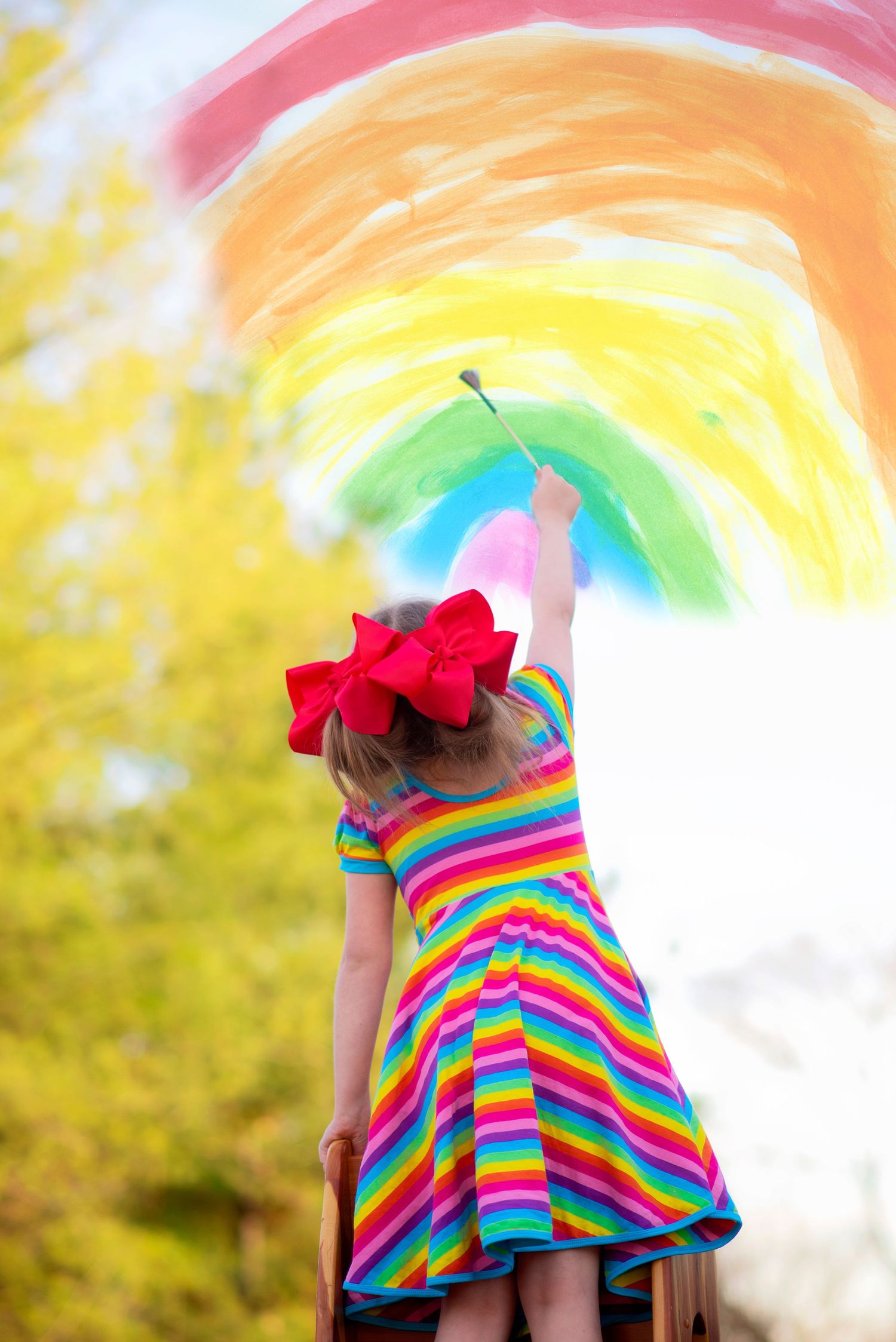 Rainbow striped dress twirling against bright sunny background.
