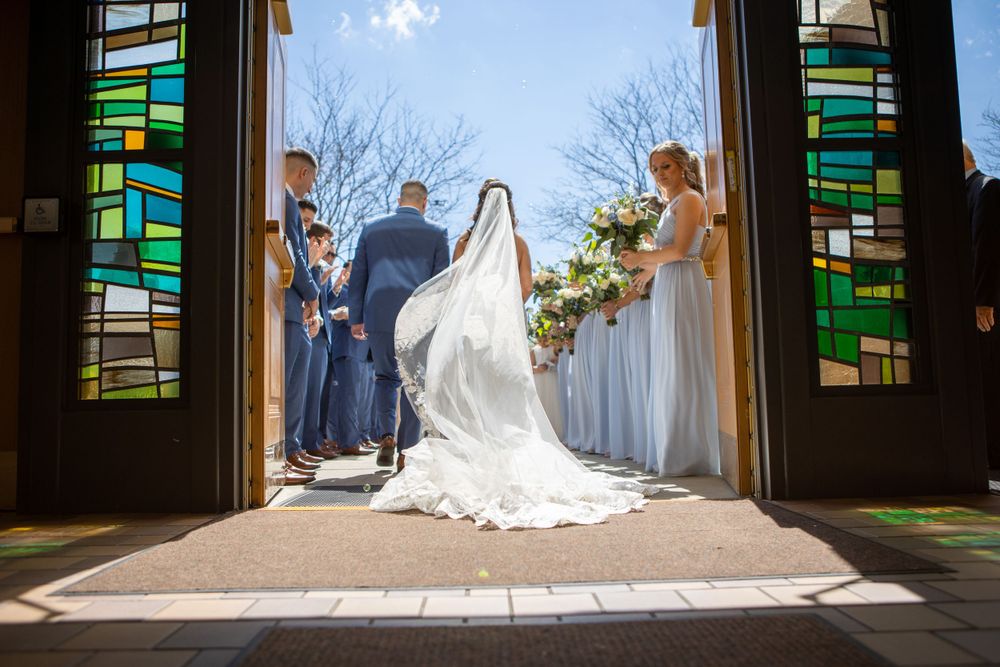 Wedding ceremony captured through stained glass church doors with dramatic lighting.