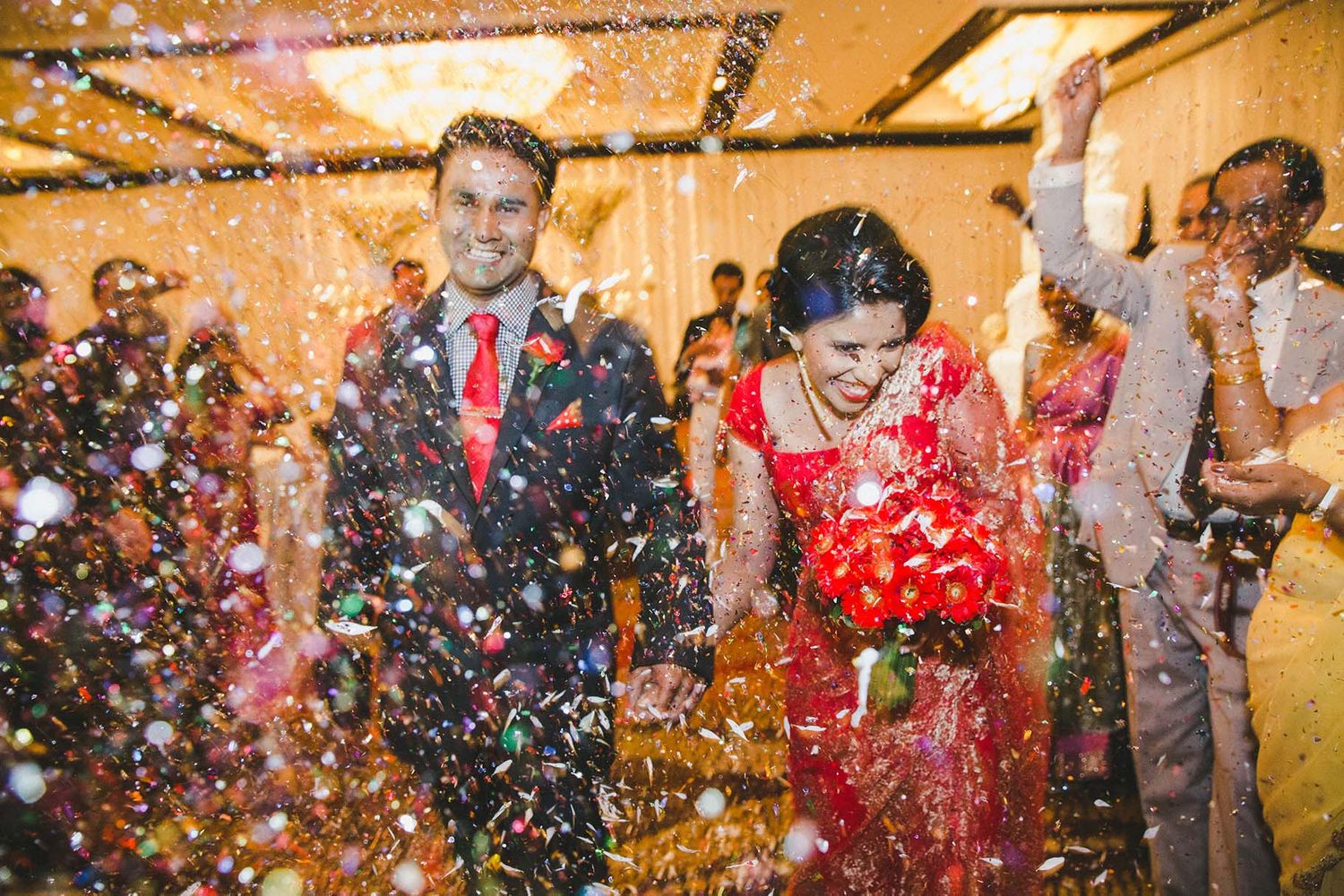 Guests celebrating at a wedding reception with colorful confetti flying through the air.