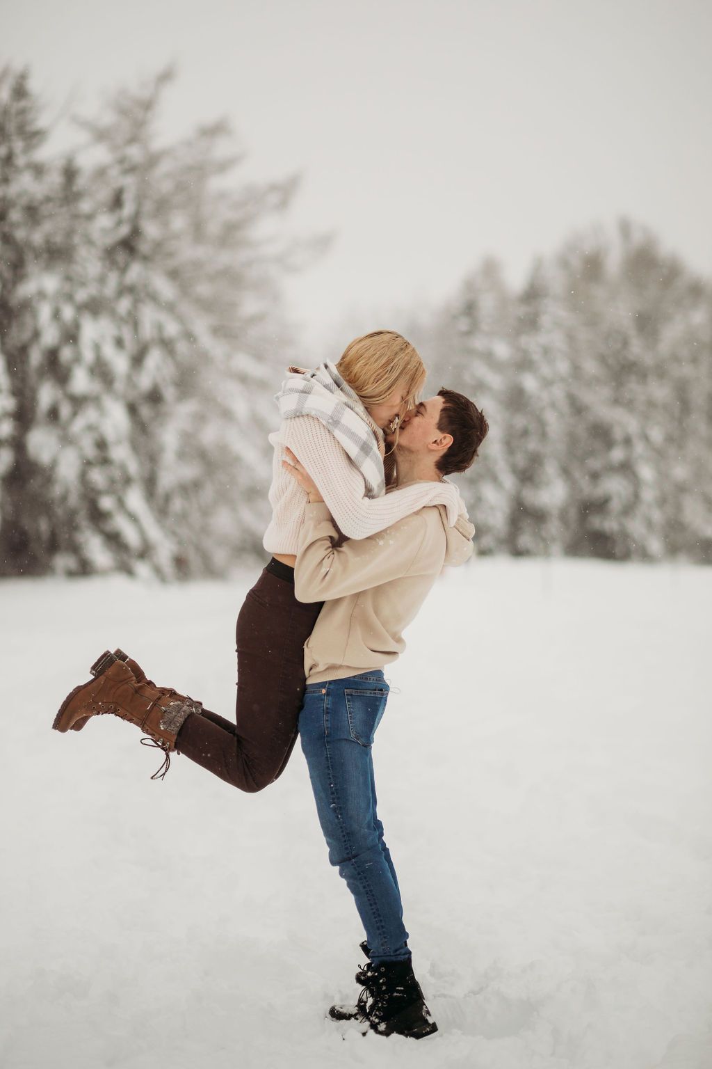 Romantic winter scene with couple embracing in snowy forest landscape.