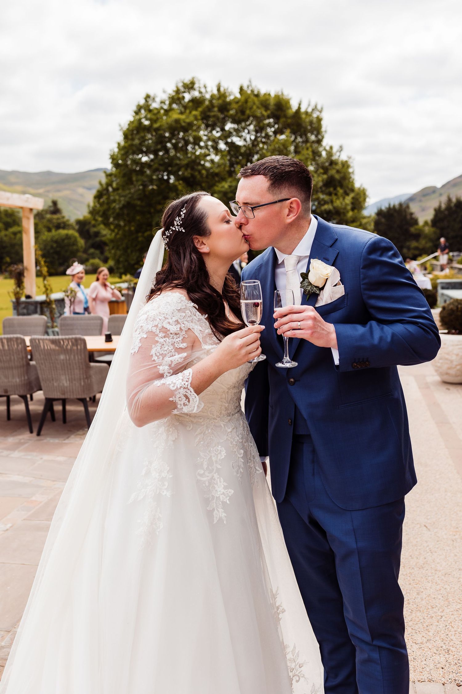 A wedding couple toasts champagne glasses at an outdoor reception venue.