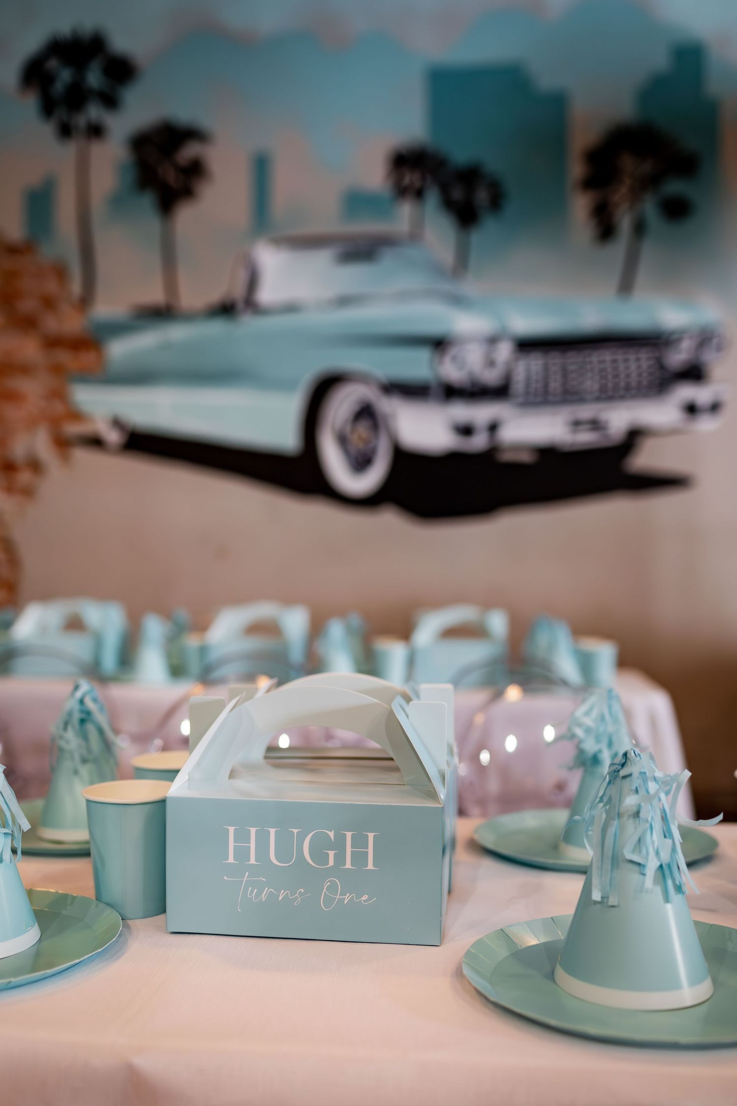 Vintage car mural with palm trees serves as backdrop for Hugh's party with mint green table settings.