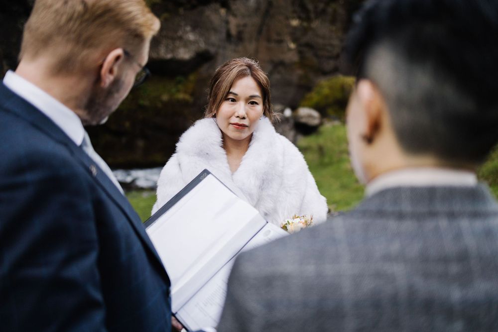 Intimate outdoor wedding ceremony with officiant and couple against rocky cliff backdrop.