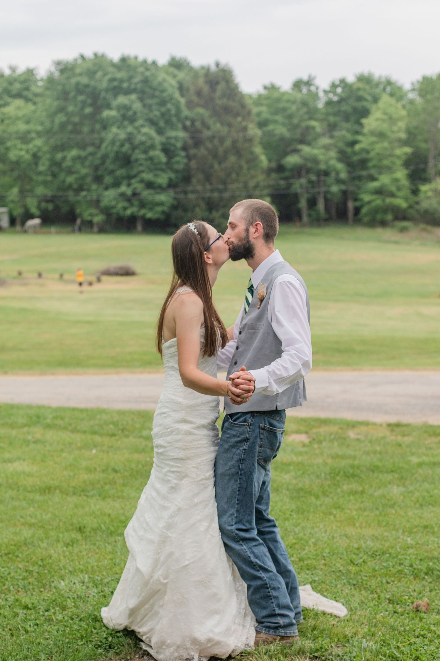 Newlyweds share a romantic dance together on grassy field during their countryside wedding.