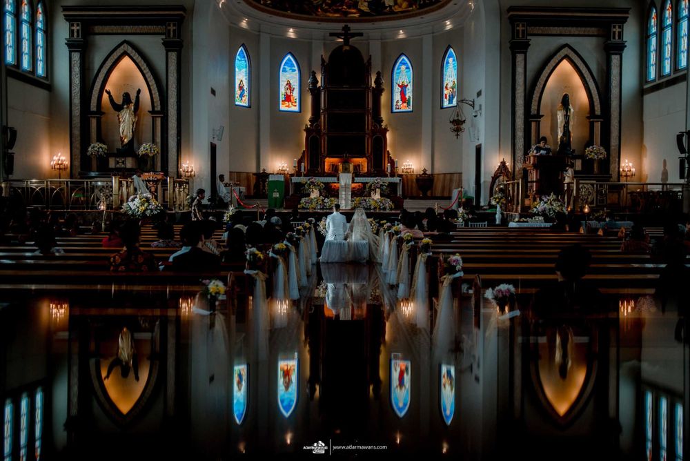 A dramatic church interior with Gothic arches and stained glass windows reflected in polished floors.