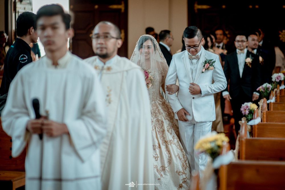 A traditional Catholic wedding procession moves through a church aisle with clergy and wedding party members.