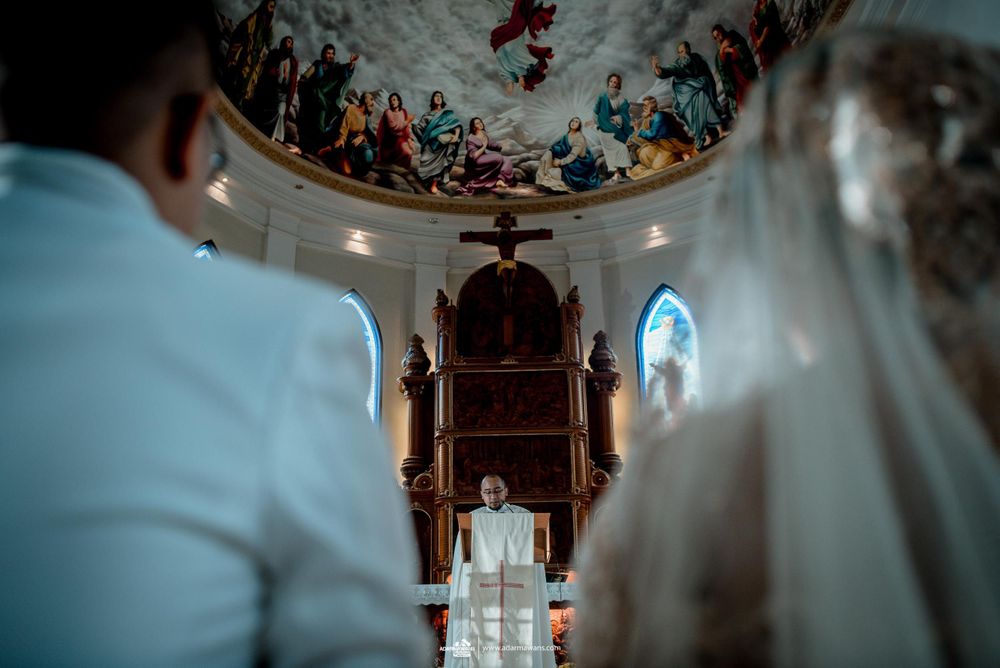 View of decorated church ceiling and altar during wedding ceremony.