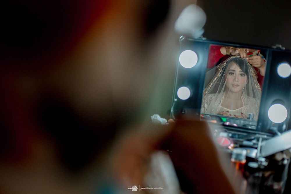 Reflection in a makeup mirror surrounded by bright lights during bridal preparation.