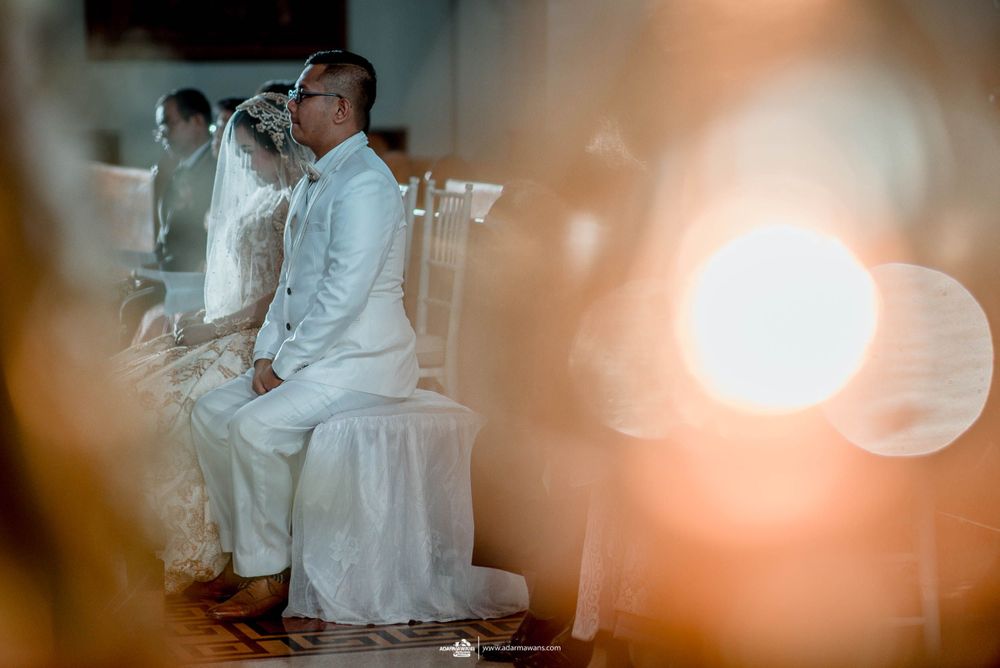 Wedding ceremony participants seated in white attire with soft focus lighting effects.