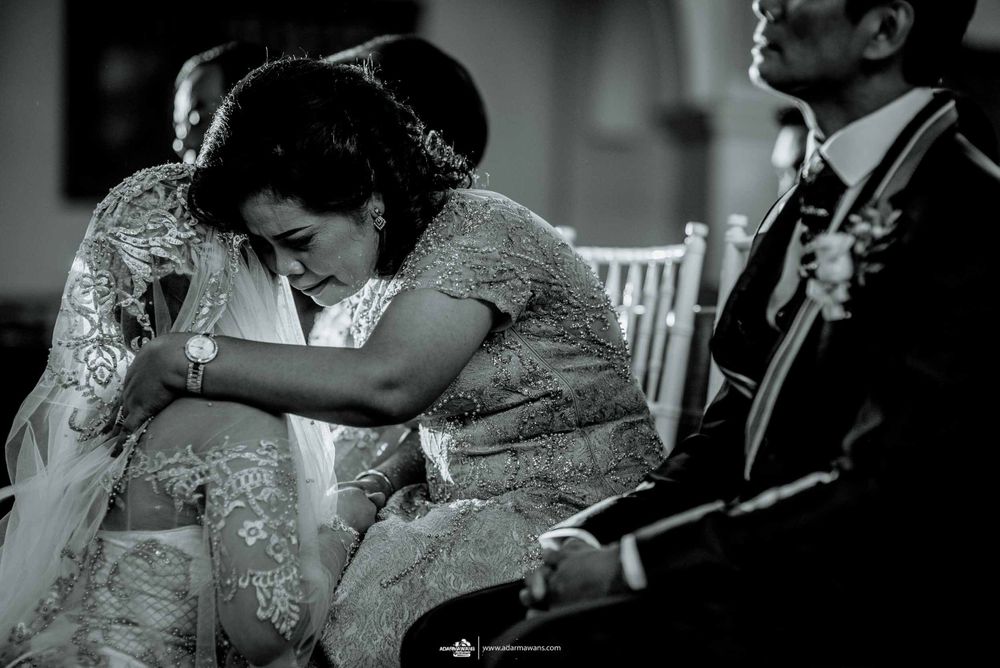 A tender black and white photograph capturing an emotional embrace during a wedding celebration.
