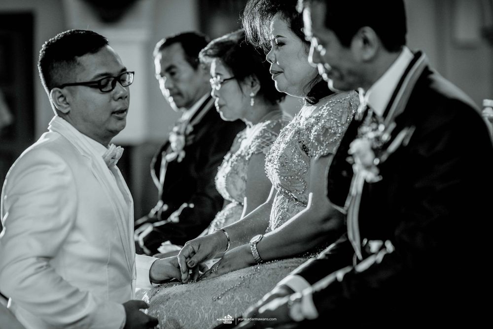 Wedding ceremony participants seated in formal attire during a black and white church service.
