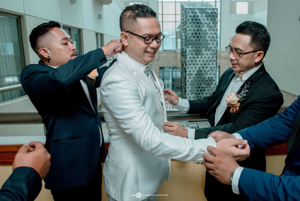 Groomsmen help adjust the groom's attire before the wedding ceremony.
