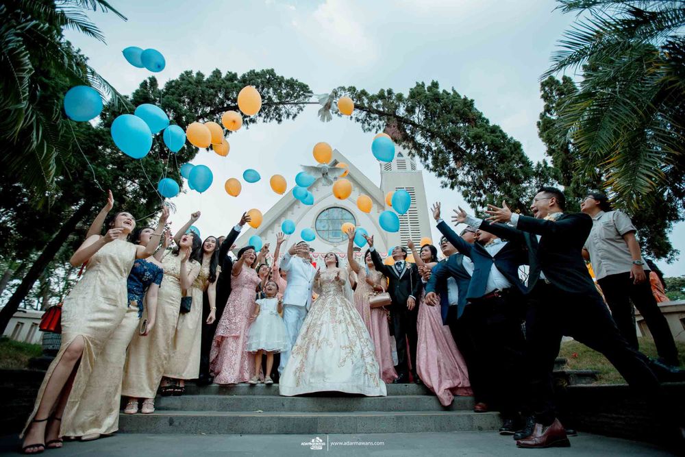 Wedding guests releasing colorful balloons during an outdoor celebration on stone steps.