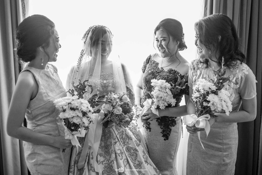 Bridesmaids in elegant dresses gather with bouquets in black and white photography.