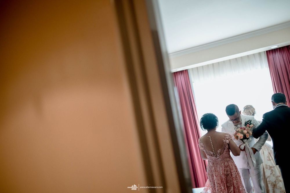 Wedding preparation scene captured through a doorway with soft lighting.