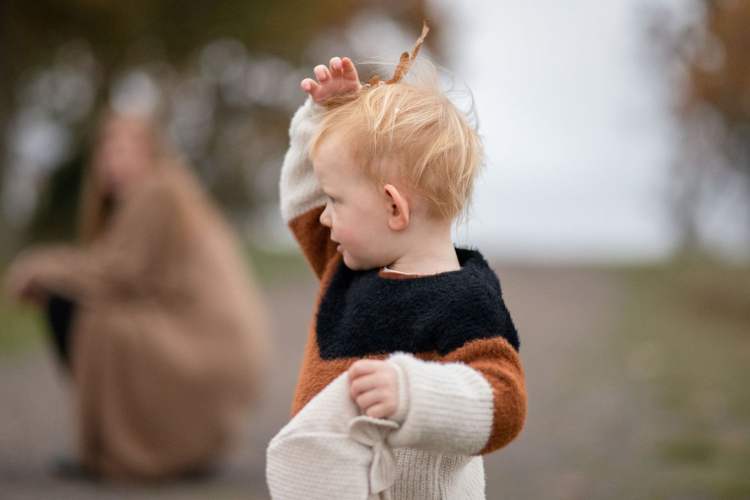 Child in colorblock sweater looking to the side against blurred background.