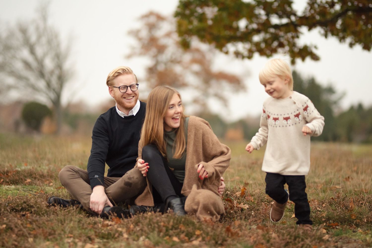 Family sharing a joyful moment together in a fall field with autumn foliage.