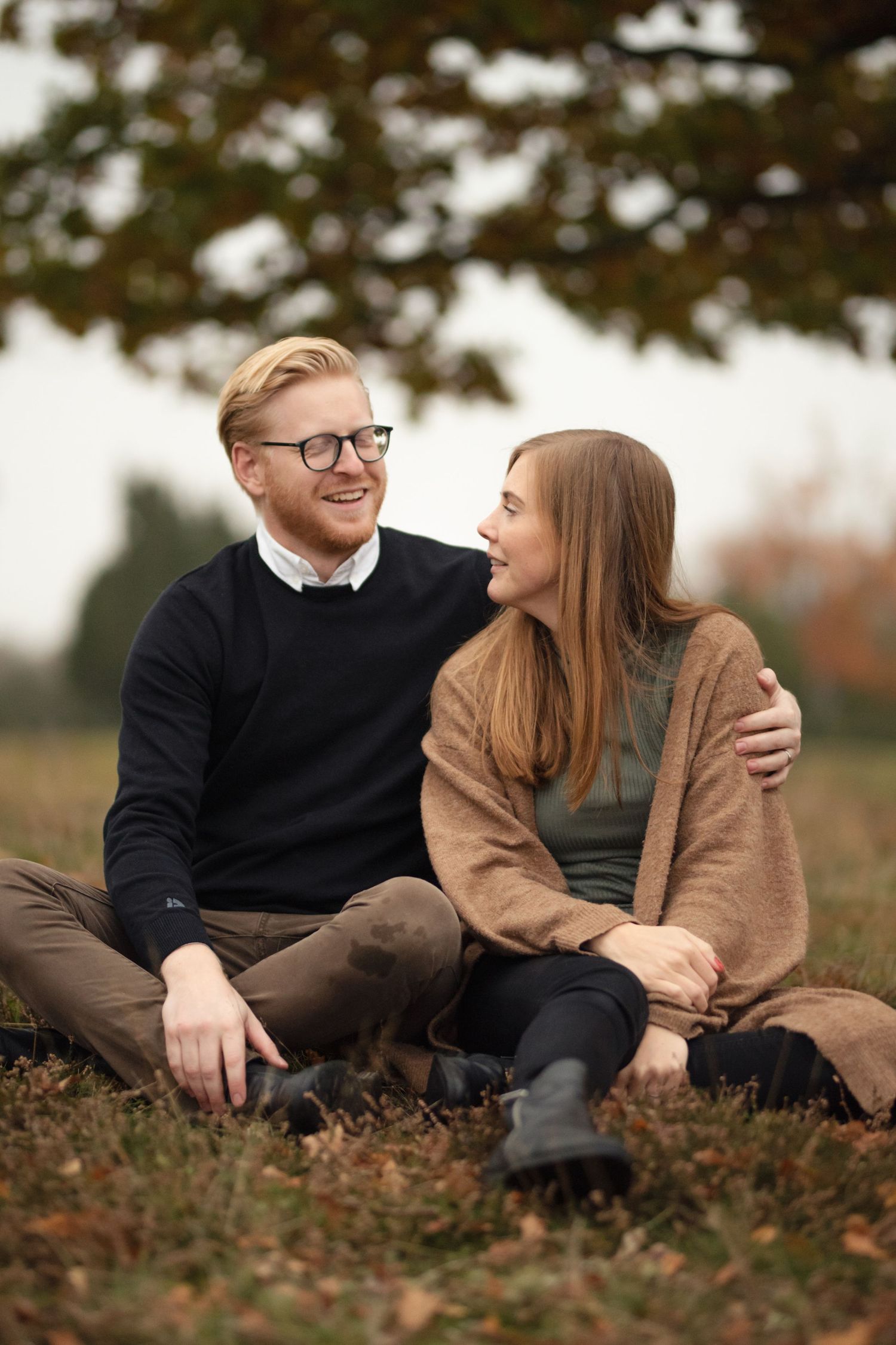 Couple sitting close together on autumn ground sharing a happy moment.
