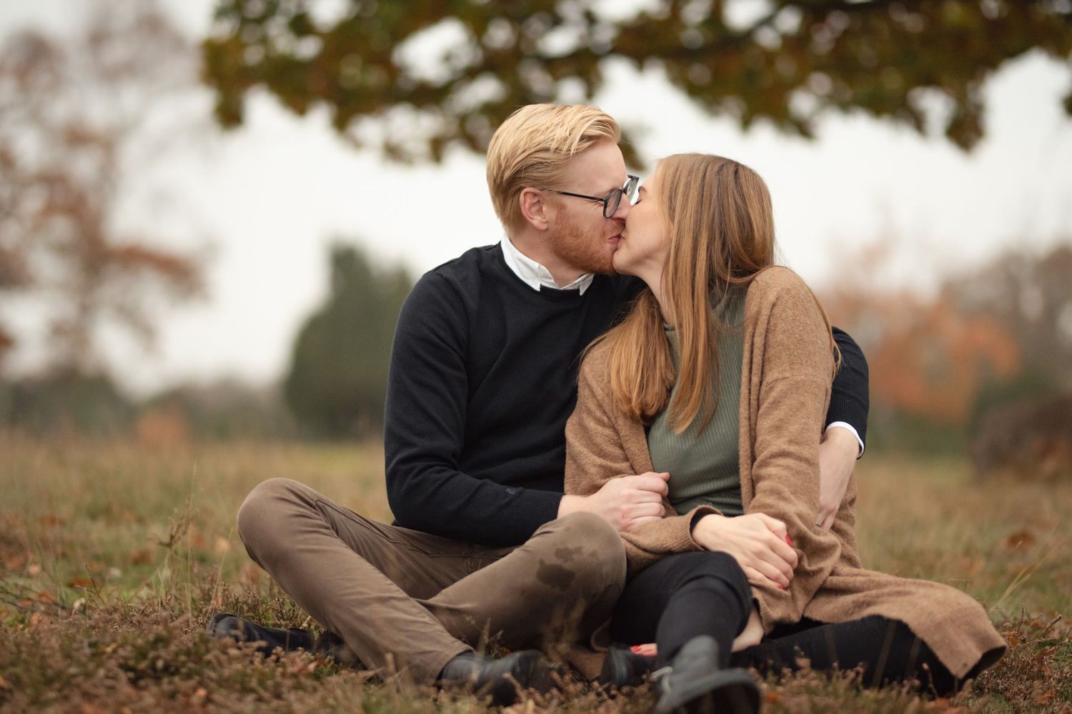 Intimate moment between couple sitting on ground during fall season.