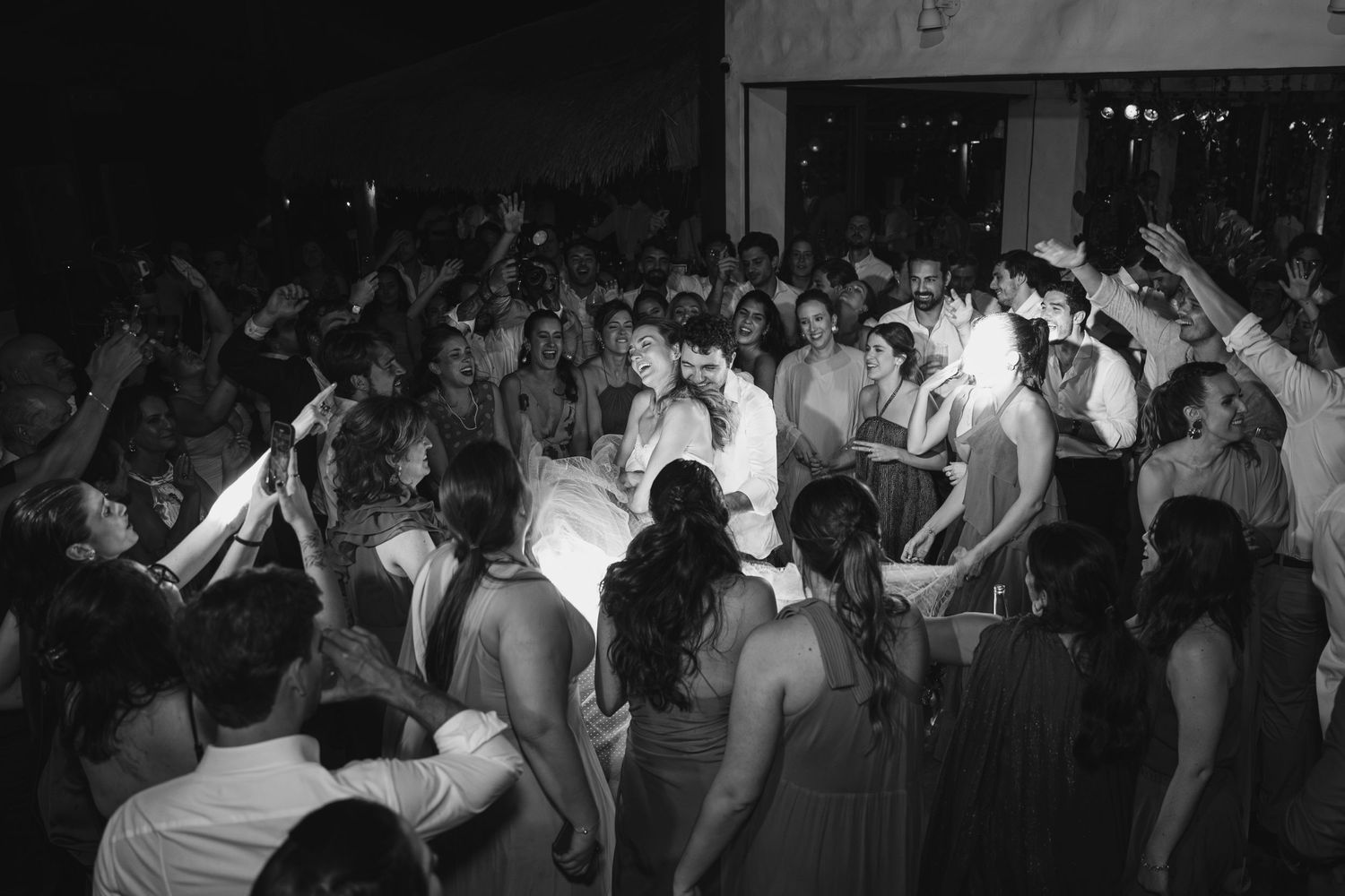 Black and white photo showing crowd of people dancing at a lively party or reception.