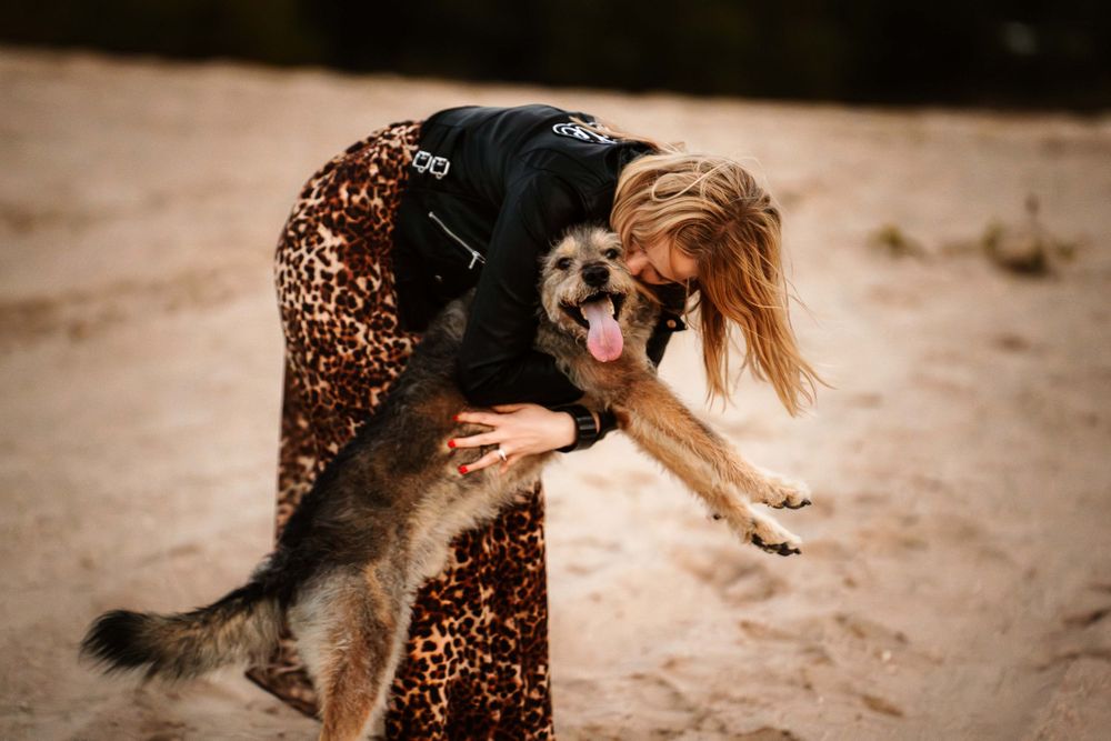 A joyful interaction between a person wearing a leopard print skirt and their excited dog.