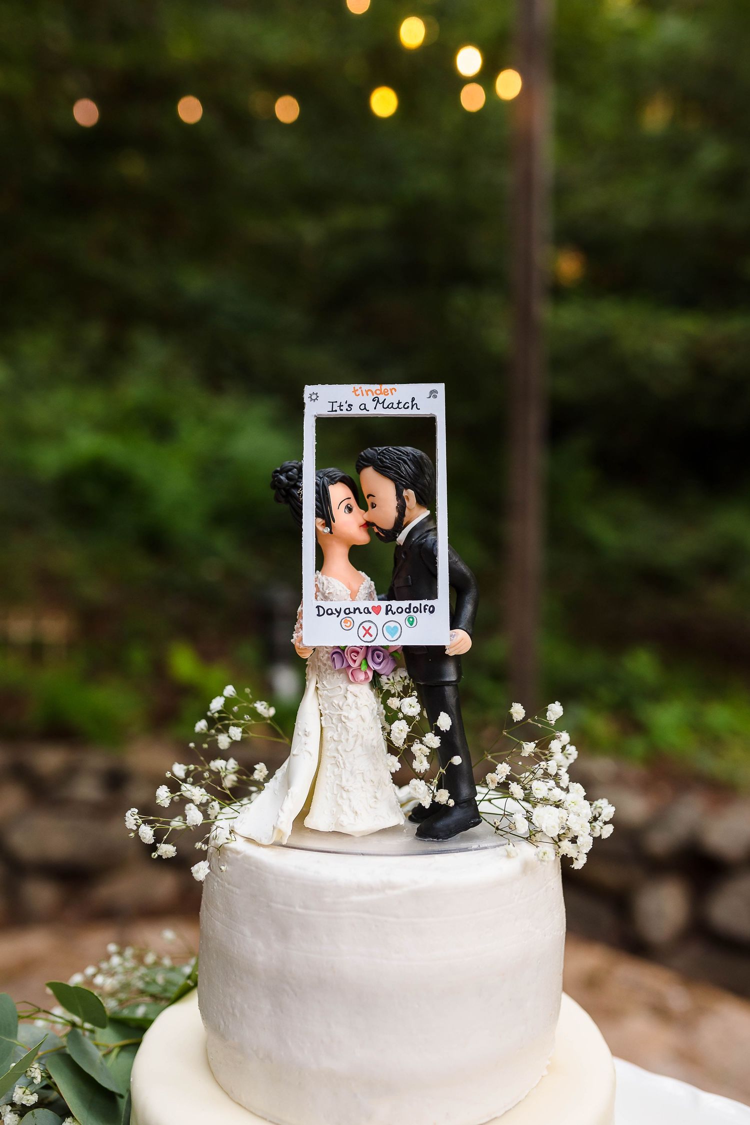 Custom photo cake topper adorned with baby's breath flowers on a white wedding cake.