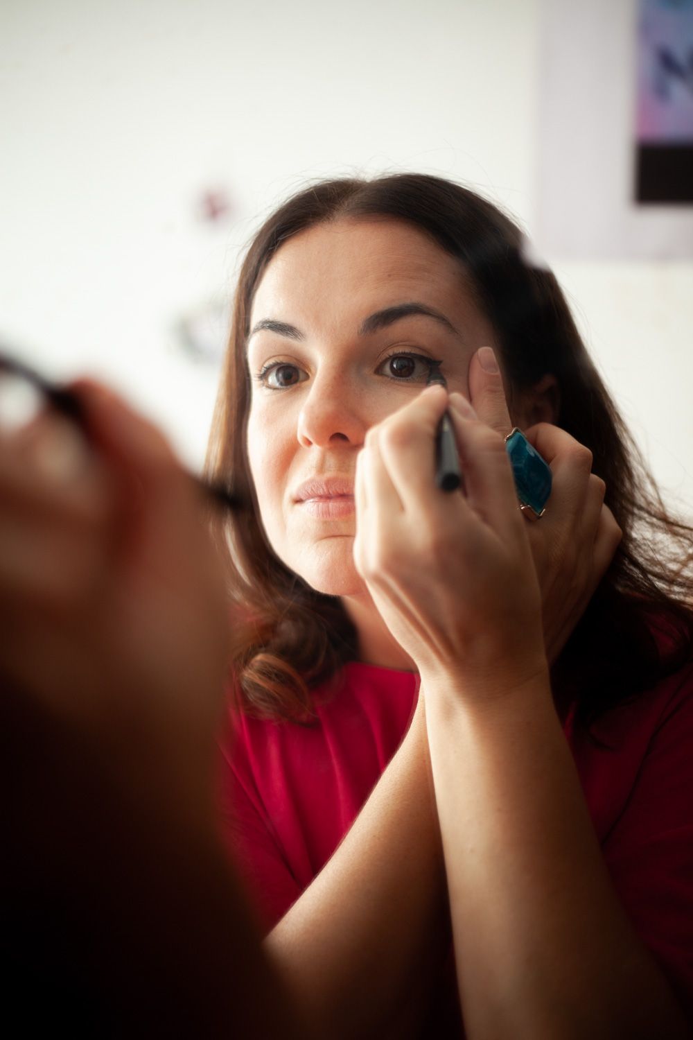 Close-up shot of someone applying eye makeup in front of a mirror.