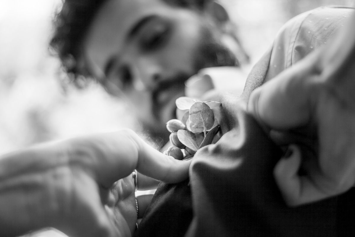 Artistic macro black and white photo showing hands delicately holding a small flower.