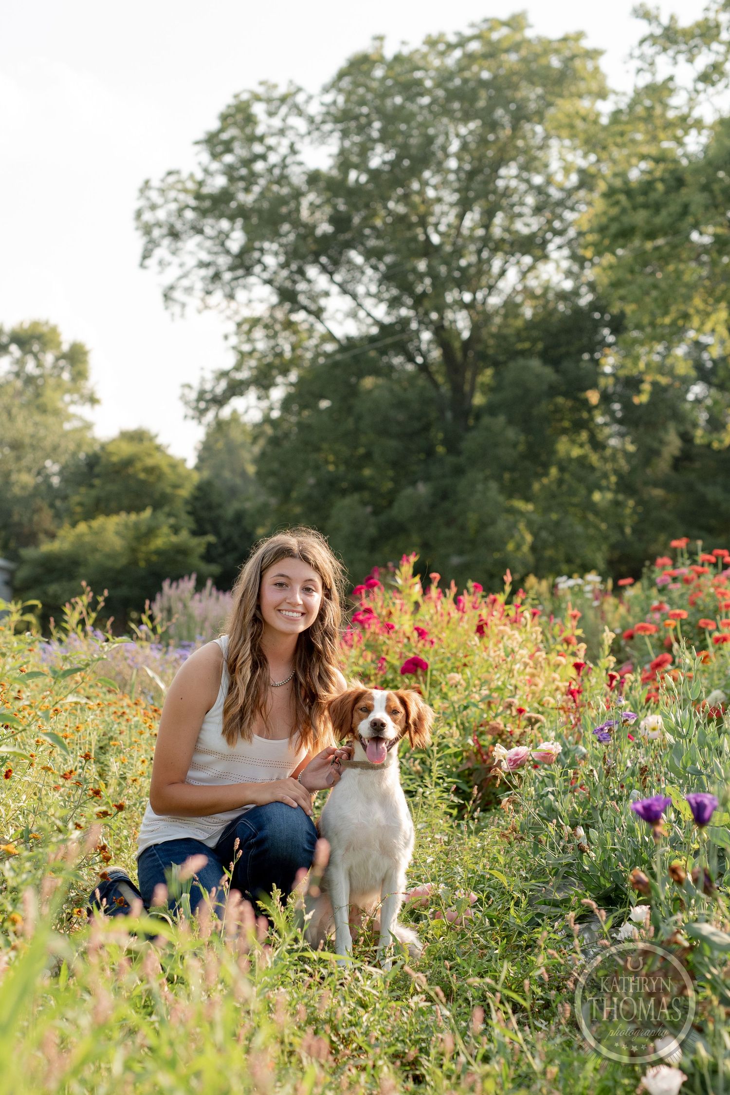 Person and friendly spaniel dog posing together in wildflower garden with pink blooms.