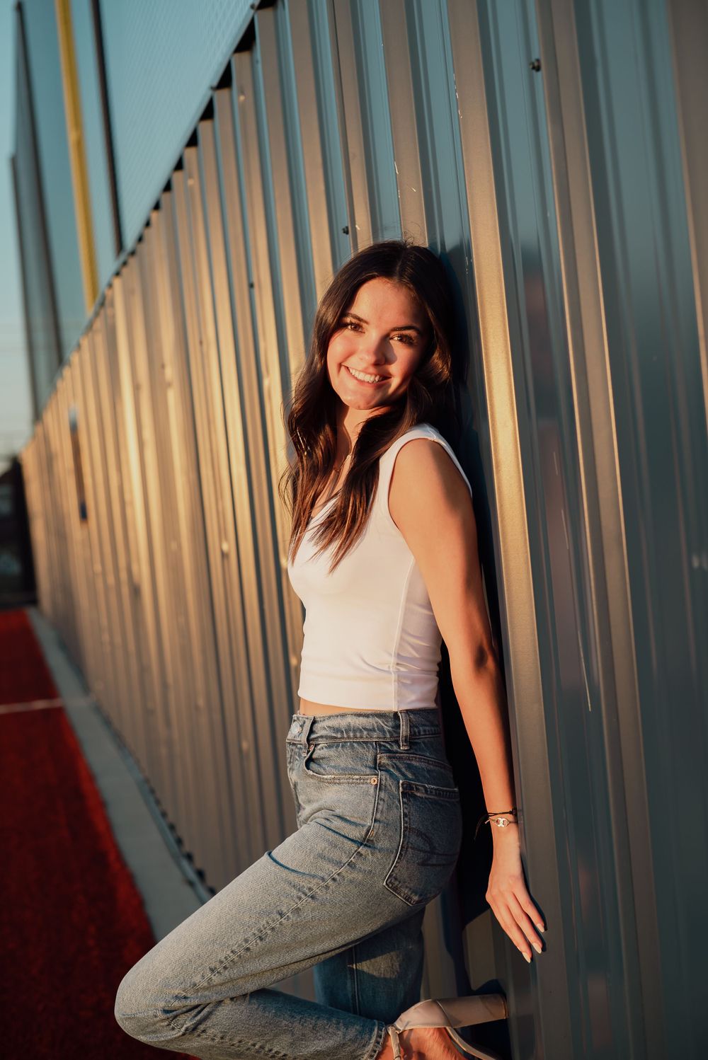 Casual portrait against corrugated metal wall during golden hour lighting.
