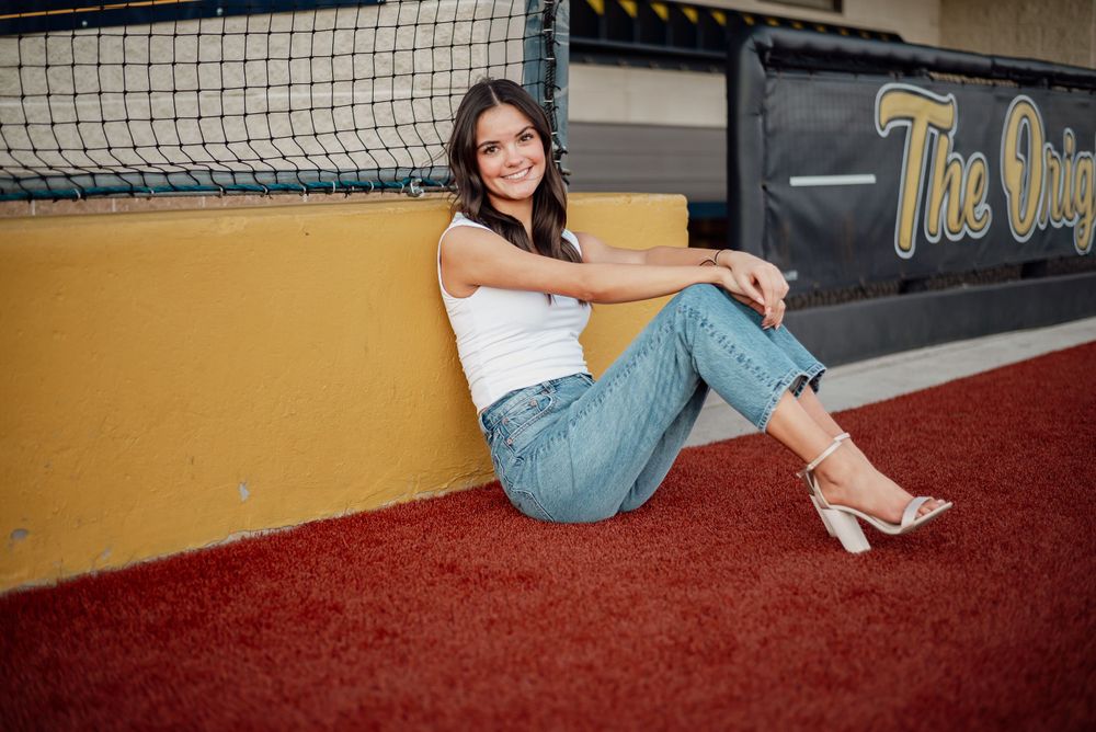 Relaxed pose by baseball netting wearing casual summer outfit.
