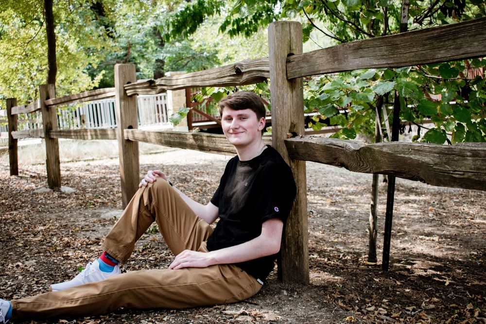 Person lounging on wooden bench in peaceful forest setting.