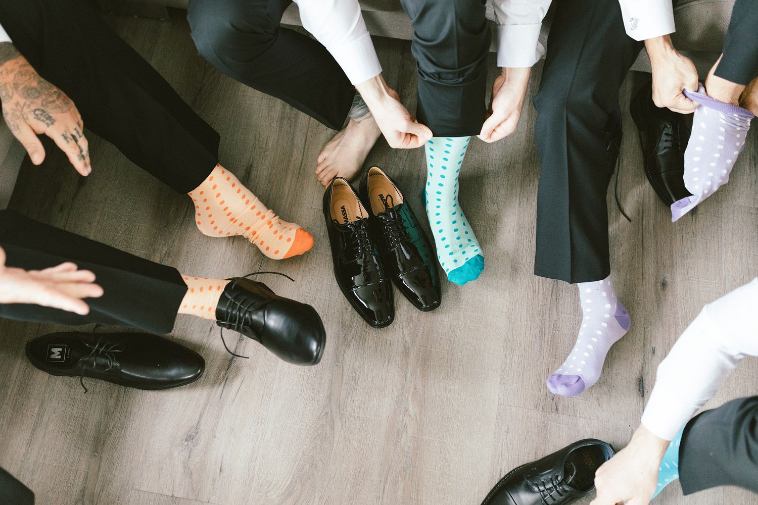 A collection of dress shoes and colorful socks shown from above on a grey wooden floor.