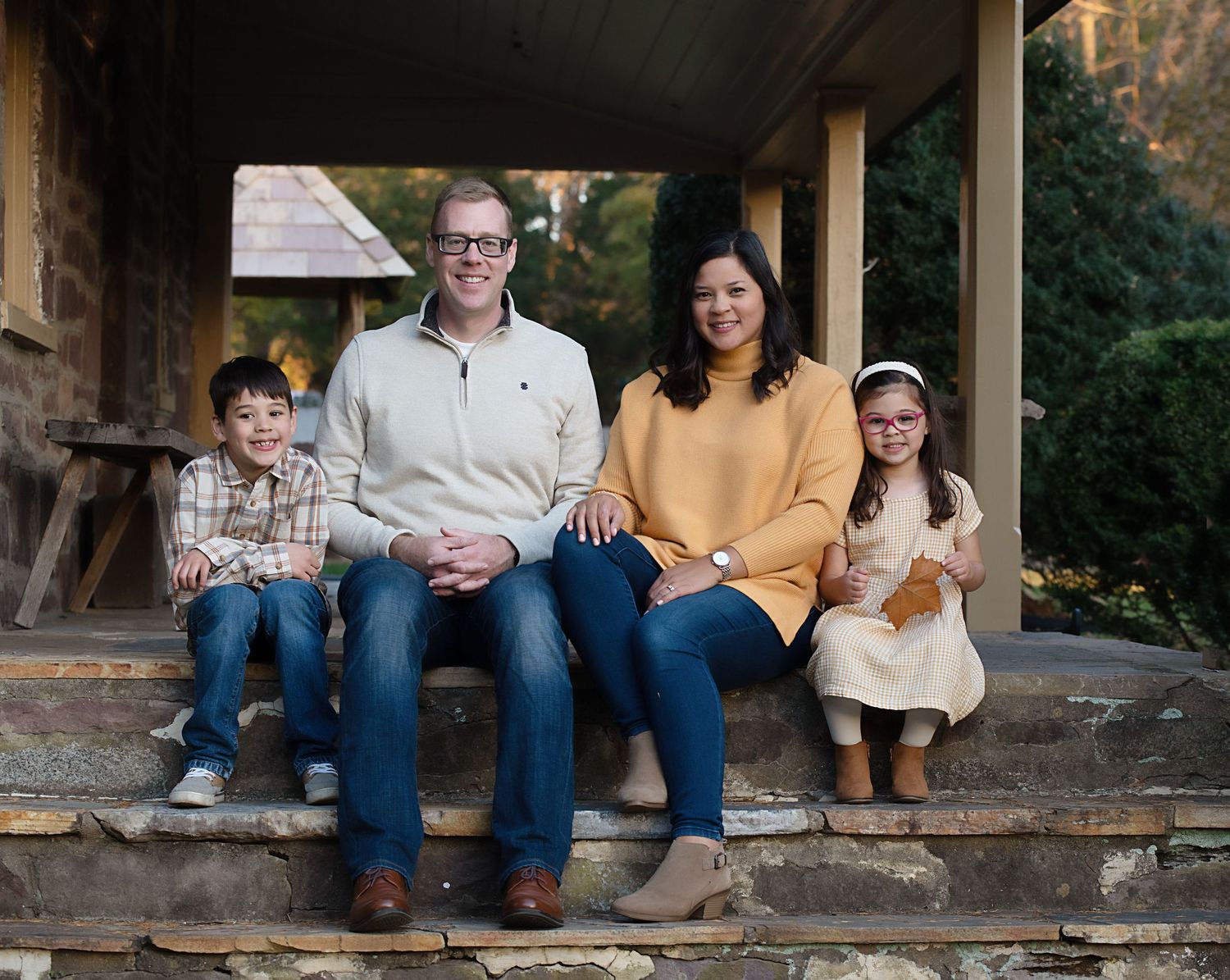 A casual family portrait on rustic wooden porch steps.