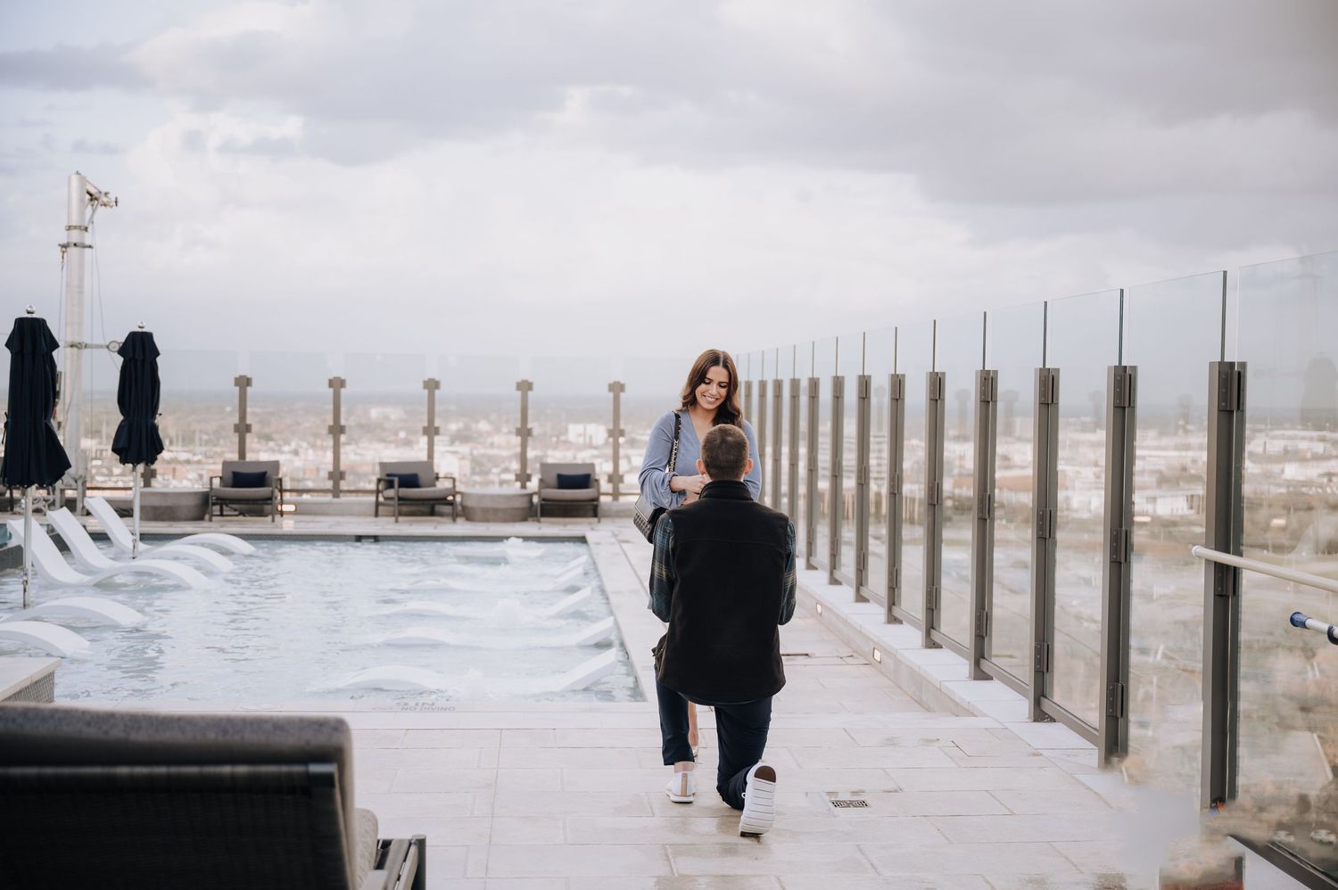 Photographer working on rooftop location with city views and glass barriers.