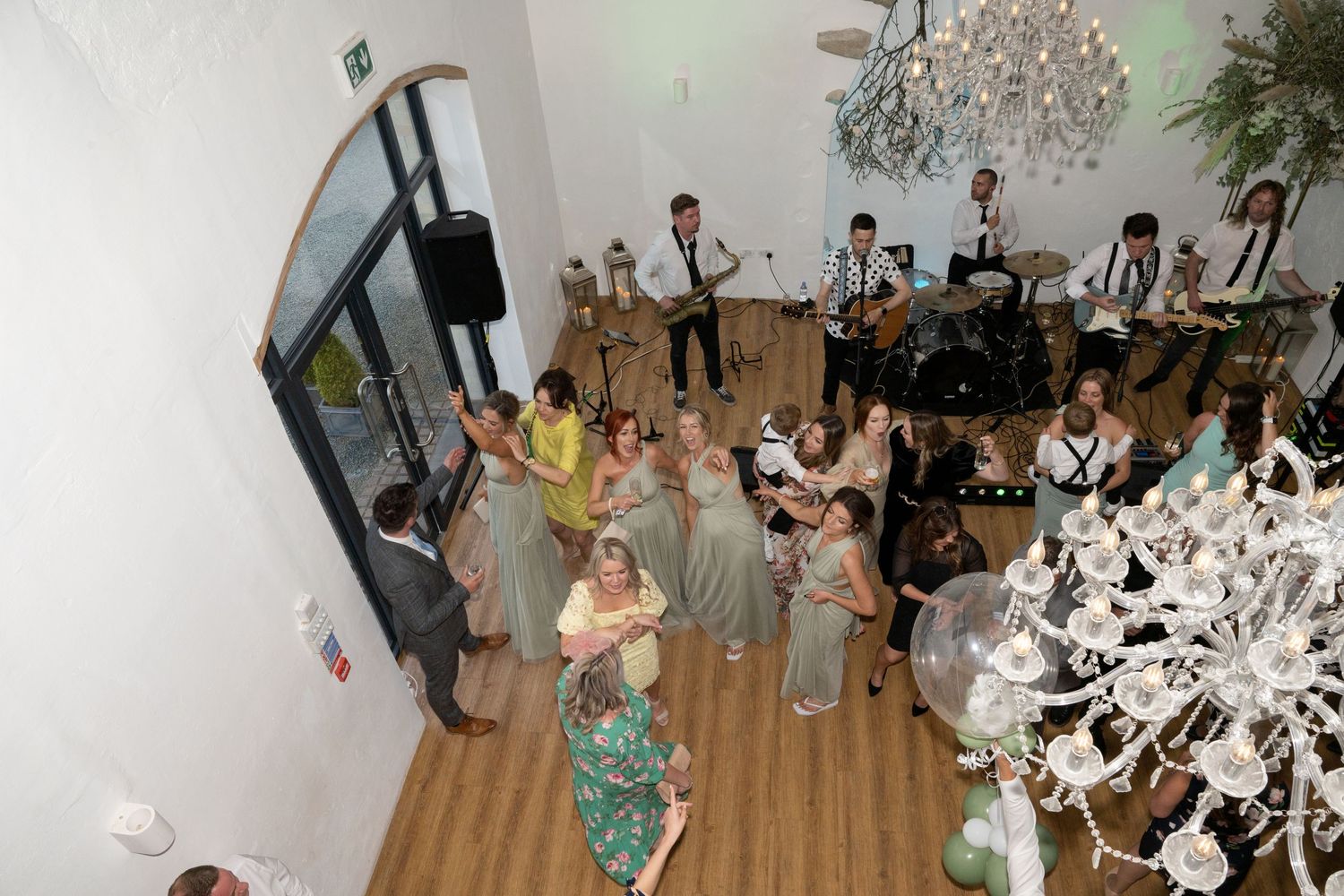 Bird's eye view of a wedding reception with chandeliers, live band and dancing guests.