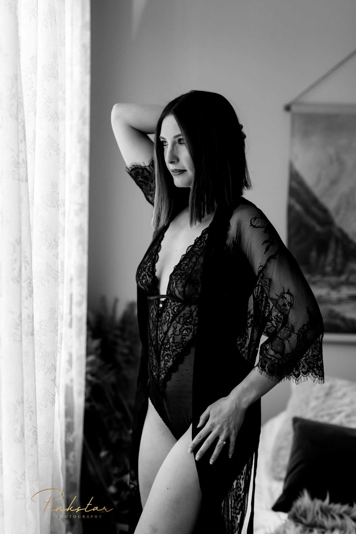 Artistic boudoir photo of woman in black lace against window light.