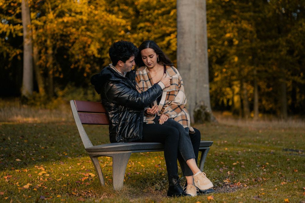 Un couple assit sur un banc avec le compagnon qui entoure sa compagne avec ses bras