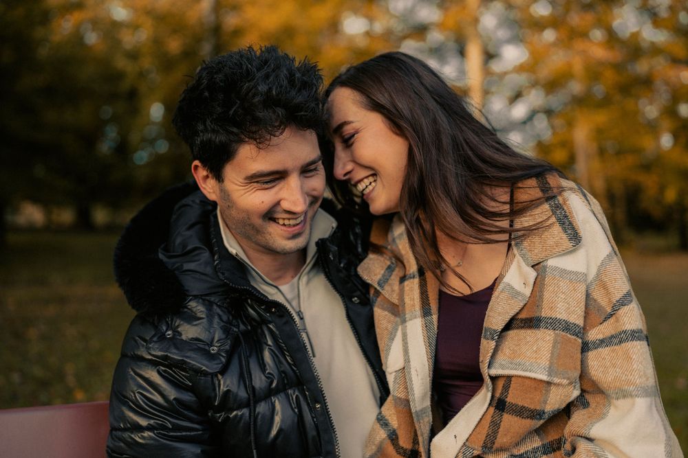 Couple assit sur un banc qui se sourit l'un à l'autre