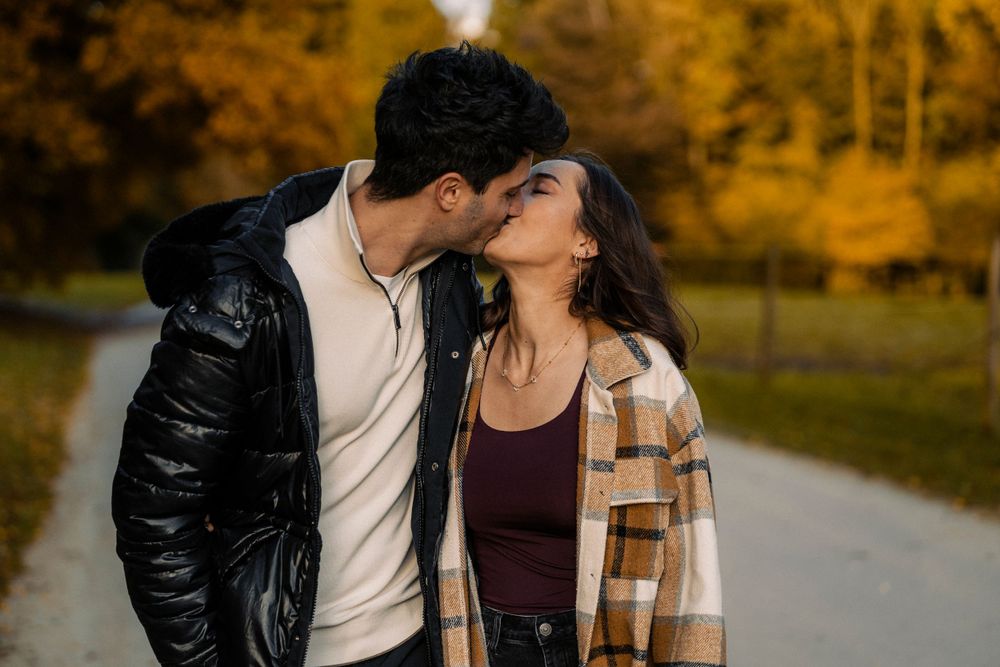 Couple qui s'embrasse au milieu d'une allée en automne