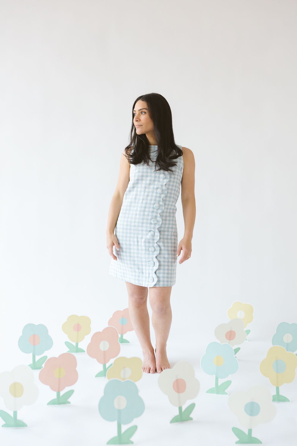 a woman wearing a white and blue Lisa Marie Fernandez dress looks away while surrounded by paper flowers, by Paula Ortiz