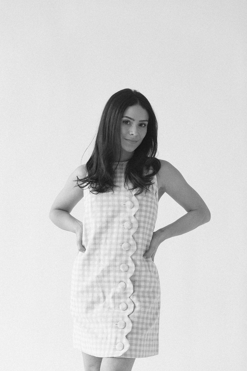 a half body view in black and white of a woman with her arms on her waist against a white backdrop, photo by Paula Ortiz