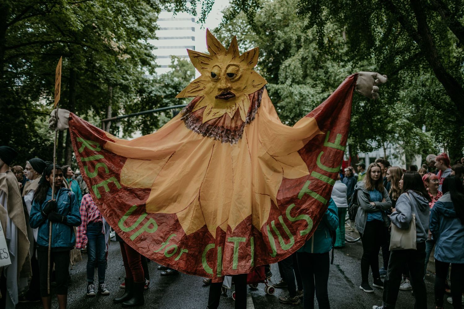 large person operated puppet of the sun that says RISE UP FOR CLIMATE JUSTICE portland oregon photojournalism