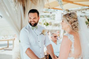 A joyful moment during an outdoor wedding ceremony under a decorated canopy.