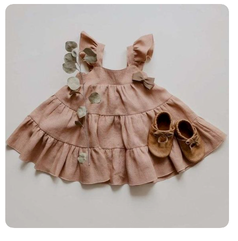 A dusty pink ruffle dress for children with matching moccasins and eucalyptus sprigs.