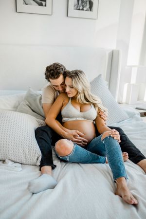 A couple relaxes together on a bed with gray pillows in a bright, modern setting.
